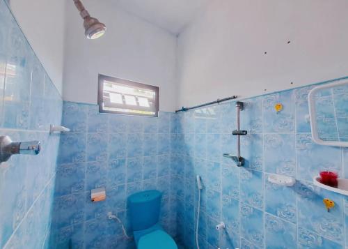 a blue tiled bathroom with a toilet and a window at Linu Villa in Hikkaduwa