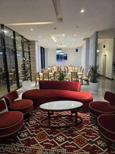 Un vestíbulo con un sofá rojo, mesas y sillas. en Authopia Hotel, en Addis Ababa