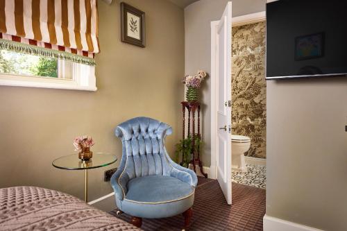 een slaapkamer met een blauwe stoel en een glazen tafel bij Brownsover Hall in Rugby