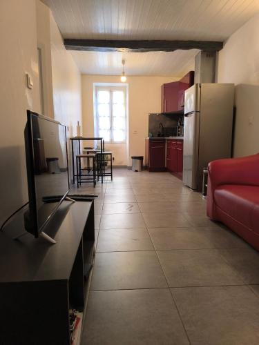 a living room with a red couch and a kitchen at Patio en Périgord in Lalinde