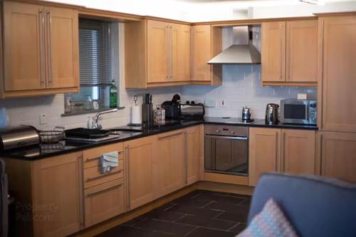 eine Küche mit Holzschränken und schwarzen Arbeitsplatten in der Unterkunft Portstewart promenade apartment with sea views in Portstewart