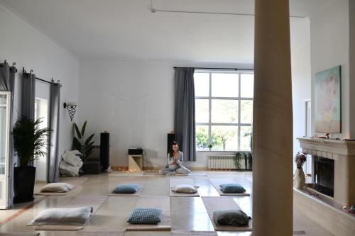 Una mujer sentada en el suelo de una sala de estar meditando en Casa do Sol Conscious Coliving, en Óbidos