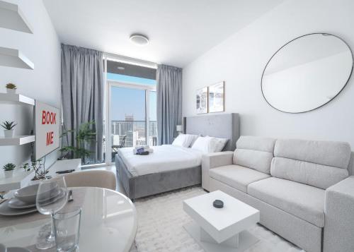 a white living room with a bed and a couch at Free housekeeping visits during your stay - StayShort - Jumeirah Village Circle Studio with Amazing Amenities in Dubai