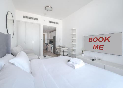 a white bedroom with two beds and a sign that reads book me at Free housekeeping visits during your stay - StayShort - Jumeirah Village Circle Studio with Amazing Amenities in Dubai