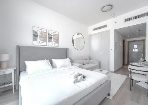 a white bedroom with a large bed and a sink at Free housekeeping visits during your stay - StayShort - Jumeirah Village Circle Studio with Amazing Amenities in Dubai