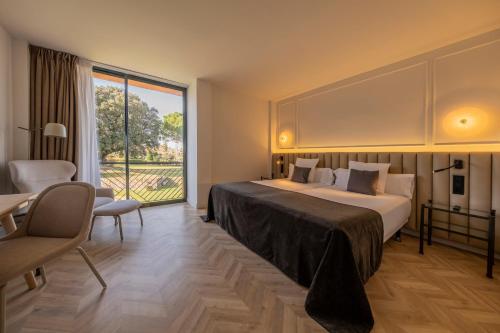 een hotelkamer met een bed en een groot raam bij Hotel TorreMirona Golf & Spa in Navata
