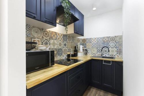 eine Küche mit marineblauen Schränken und einer Mikrowelle in der Unterkunft Cozy Beachside Falla by Elite Apartments in Zaspa