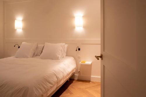 a bedroom with a bed with two lamps on the wall at Hotel Montaigne in Ostend