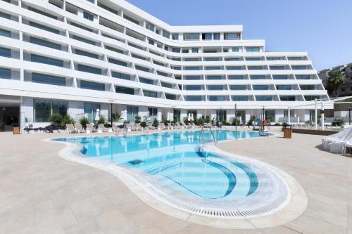 un grande edificio con una piscina di fronte a un edificio di AKOYA HOTEL a Eilat