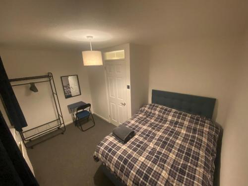 une chambre avec un lit avec une couverture à carreaux dans l'établissement Home in Ty Canol, Cwmbran, à Cwmbrân