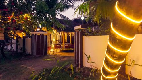 a house with a fence and a tree with lights at Marari Beach La Vista in Mararikulam