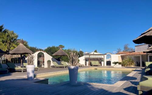 a pool with chairs and umbrellas in a resort at Mas des Rièges & Spa in Saintes-Maries-de-la-Mer