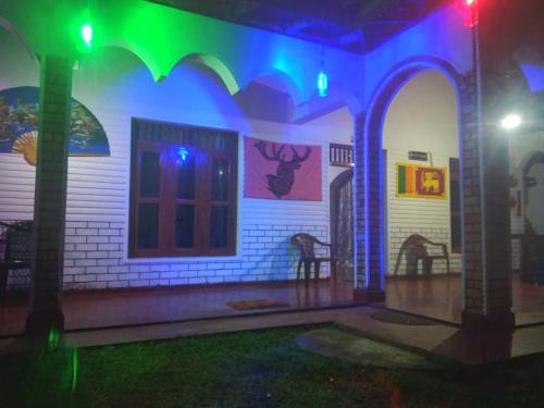 a house lit up with green and blue lights at Sigiriya Lions Rest Hostel in Sigiriya