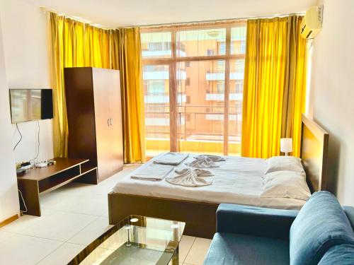 Un dormitorio con una cama y un sofá y una ventana. en Grand Kamelia apartments, en Sunny Beach