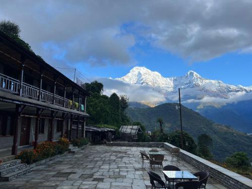 a patio with tables and chairs with mountains in the background at RJ Boutique Hotel - Ghandruk in Astam