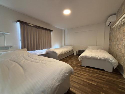 a bedroom with two beds and a window at とまるん桜山 in Nagoya
