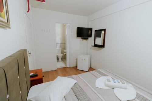 a white room with a bed and a tv at Hotel Centro dos Canyons in Praia Grande