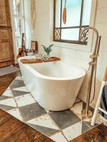 Una gran bañera blanca en un baño con ventana. en Secluded Treehouse Rental Ideal for Glamping in Alabama, en Brushy Pond
