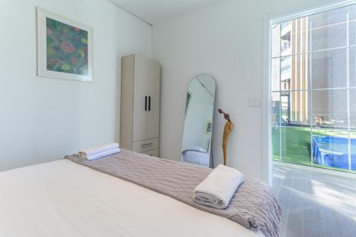 a white bedroom with a bed and a mirror at GlassHaus Rooftop 2-BR W Pool & Terrace in Ghazir in Admā