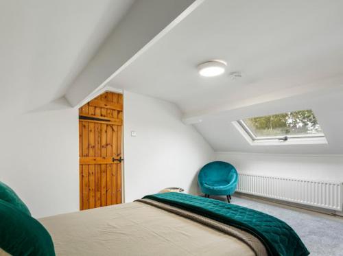 a bedroom with a bed and a blue chair at 7 Guests - 6 Bedroom - Free Wi-Fi - NN15 in Burton Latimer