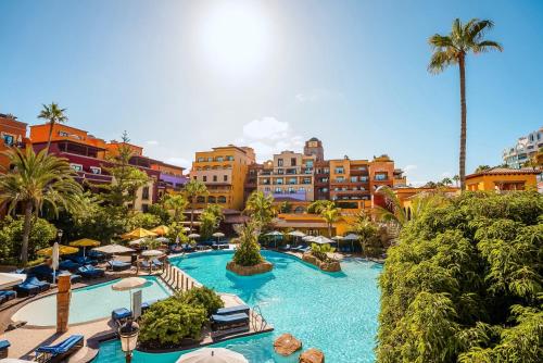 a resort pool with chairs and umbrellas and buildings at Europe Villa Cortes GL in Playa de las Americas
