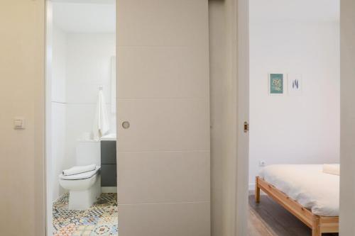 a white bathroom with a toilet and a bed at Lofty Justa in Seville