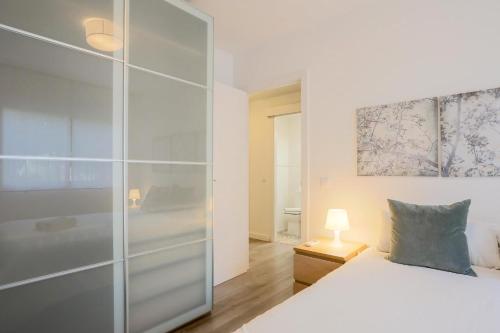 a bedroom with a white bed and a glass closet at Lofty Justa in Seville