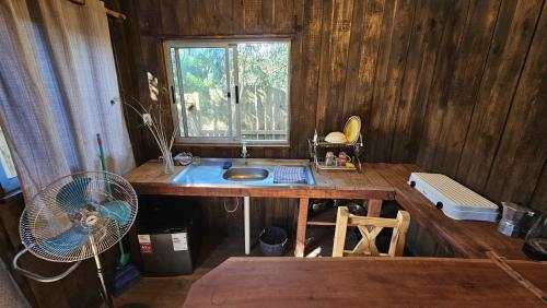 a kitchen with a sink and a window and a fan at Kosmik House in Punta Del Diablo