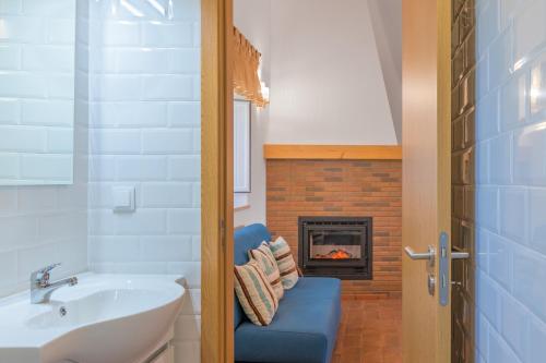 a bathroom with a blue chair and a fireplace at Casa Da Ti Vanda in Zambujeiras
