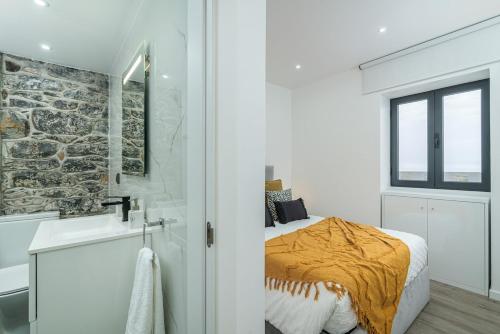 a bedroom with a bed and a bathroom with a sink at Sunny Side II Free heated pool in Tábua