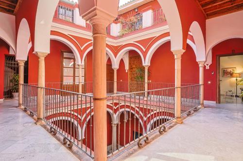 an arcade in a building with red walls and columns at Casa Palacio Guiomar by SHS in Seville