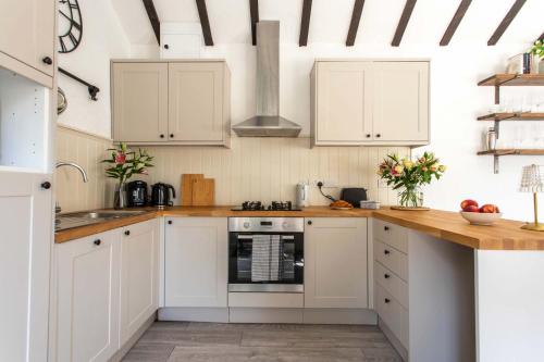 WoolvertonにあるThe Cowshed - Country Retreatのキッチン(白いキャビネット、木製カウンタートップ付)