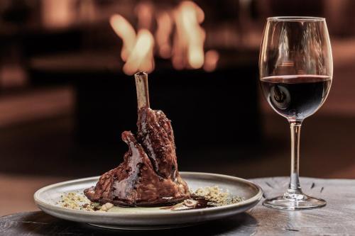 een stuk vlees op een bord naast een glas wijn bij MIM Baqueira Member of Melia Collection in Baqueira-Beret