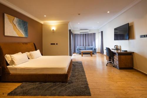 een slaapkamer met een bed, een bureau en een stoel bij Nouveau Hotel in Accra