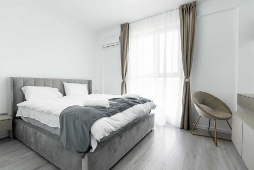 a bedroom with a bed and a chair and a window at Hori Residence - Confort și Stil în Băile Felix in Cordău