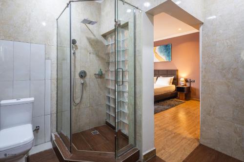 een badkamer met een douche, een toilet en een bed bij Nouveau Hotel in Accra