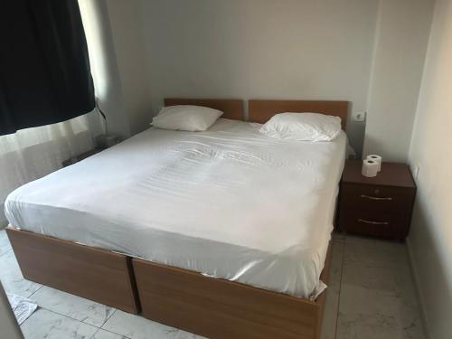 a bed with a wooden frame and white sheets and pillows at NR1 Pansiyon in Canakkale