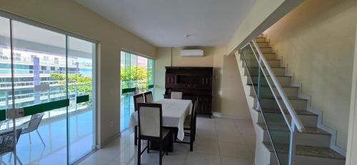 een eetkamer met een tafel en een trap in een huis bij Triplex Penthouse with Private Pool and Sea View in Rio das Ostras