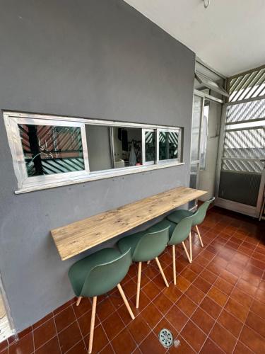 a table and some green chairs in a room at Quartos Vila Olímpia 1 in Sao Paulo