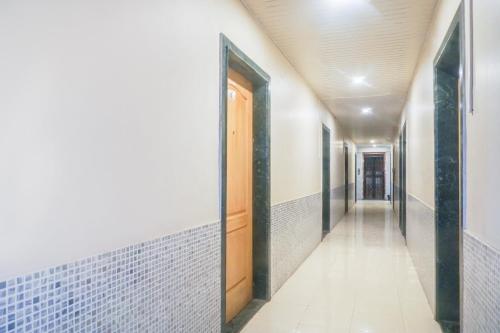 a hallway with white tile walls and a wooden door at Hotel O Atithi Lodge in Wagholi