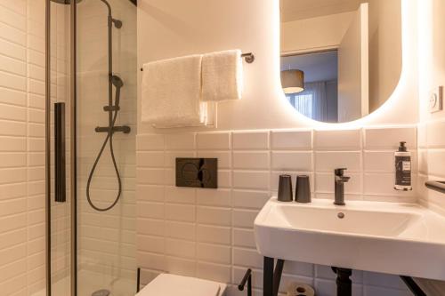 Un baño con lavabo y ducha con espejo. en Dantan Hôtel, en Boulogne-Billancourt