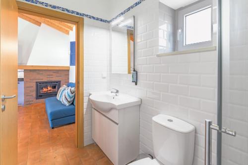 Un baño blanco con inodoro y lavabo. en Casa da Ti Mónica, en Zambujeiras