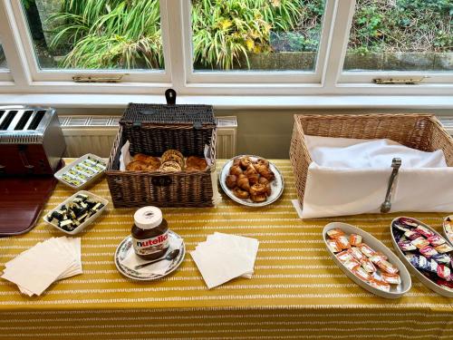 スワネージにあるLouisa Lodge & Purbeck House Hotelのクッキーやその他の食べ物の入ったバスケットが置かれたテーブル