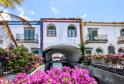 an exterior view of a building with pink flowers at Vv Velero in Puerto de Mogán