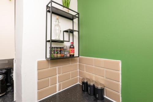 a corner of a kitchen with a green wall and shelves at Llangefni Town Centre 3 Bed Apt & Free Parking in Llangefni