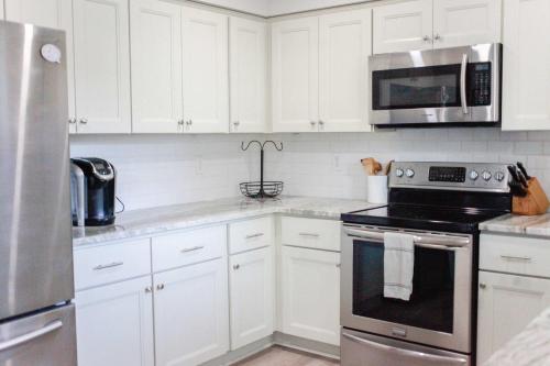 a kitchen with white cabinets and a stove and microwave at Sojourn Delightful Family Home Sleeps 6 in Norfolk