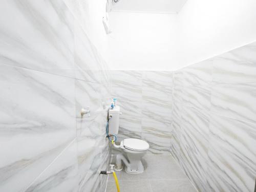a bathroom with a toilet in a white tiled wall at OYO 91244 Aufa Chalet in Kampong Ru Tujoh