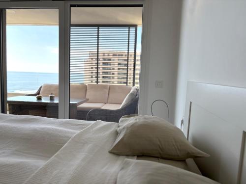 een slaapkamer met een bed en uitzicht op een woonkamer bij PANORAMA MAR - Primera Linea - Lujo in Torrevieja