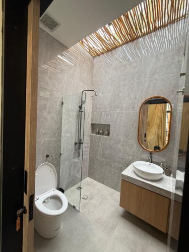 ein Badezimmer mit Toilette, Waschbecken und Spiegel in der Unterkunft Amigo uluwatu in Uluwatu