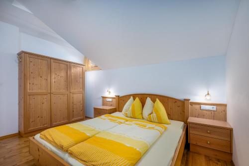 a bedroom with a bed with yellow sheets and wooden cabinets at Wieserhof Vals in Valles